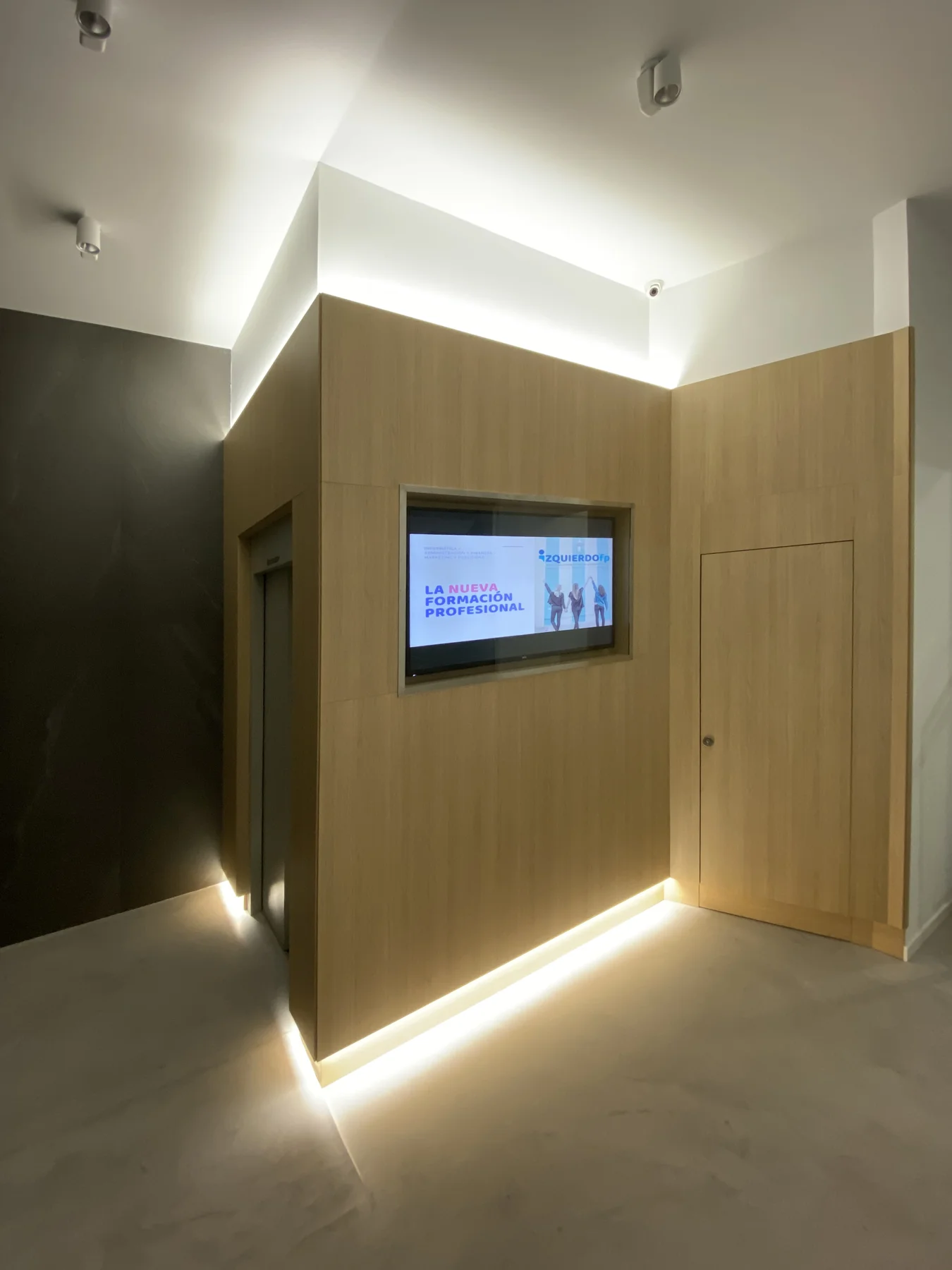 Vestíbulo de Izquierdo FP con pantalla integrada en un panel de madera e iluminación inferior.