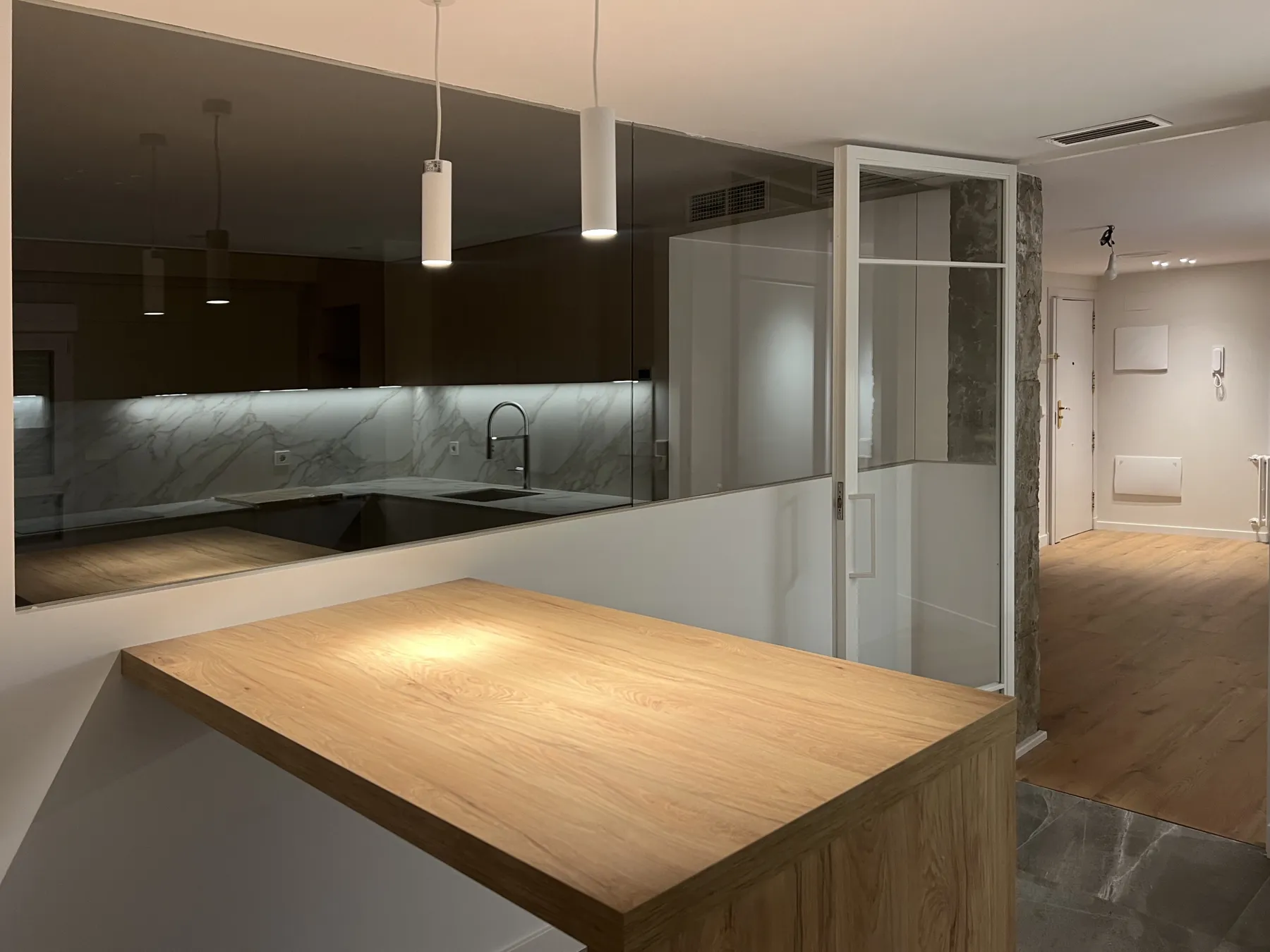 Barra de madera junto a la cocina y una puerta acristalada plegable.