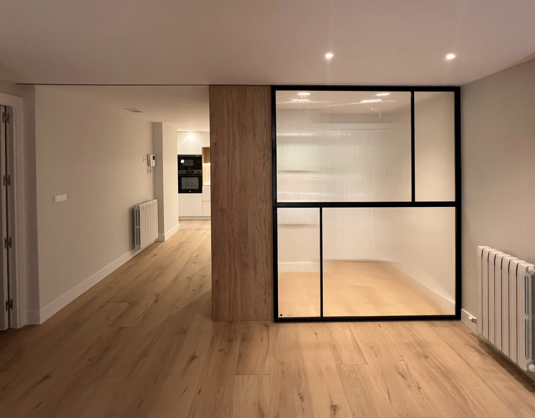 Cerramiento acristalado junto a un panel de madera en la zona de día del piso García.