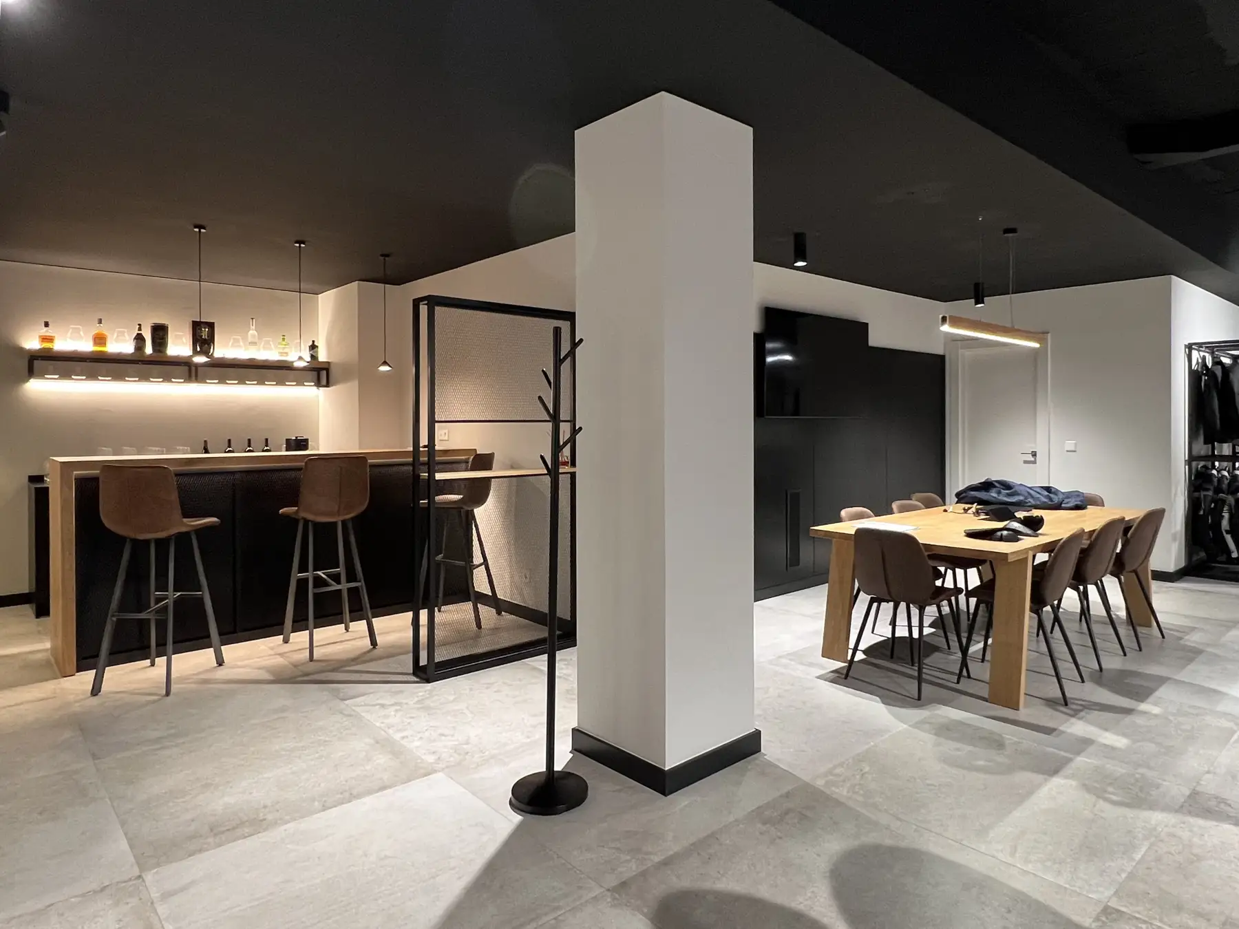 Zona común de Unik con mesa de madera, sillas y barra con taburetes.